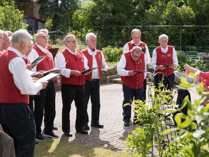 Ein Männerchor singt unter freiem Himmel